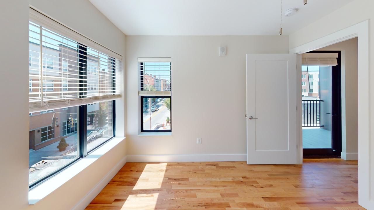 A room with a wooden floor and a window with blinds.